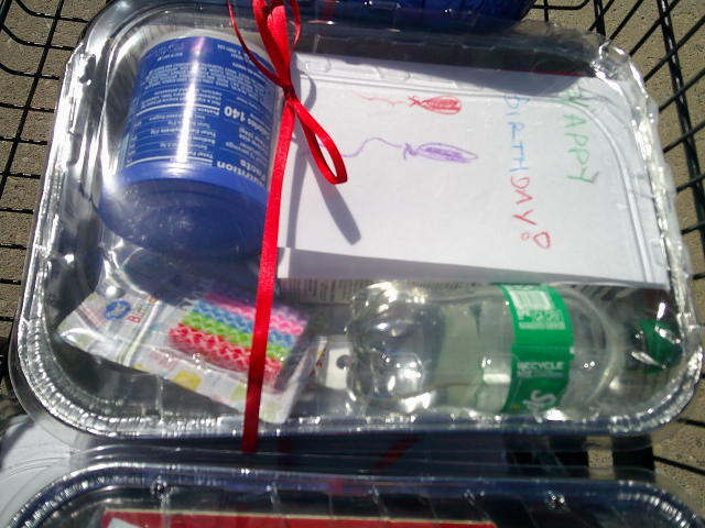 Tin foil pan with candles, frosting, cake mix, card, and sprite.